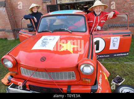 22 marzo 2019, Sassonia-Anhalt, Halle (Saale): l'azione artista Rolf Becker alias Drehorgelrolf sorge accanto al suo Trabi 601 station wagon, che si erge su un telecomando ed è decorato con ritratti di Ho Chi Minh e una stella. In aprile, il 71-anno-vecchio piani di viaggio in Vietnam per quattro settimane con la Trabi e il suo partner di Margrit B. Krüger (l) e la distribuzione di farmaci ad azione Medeor. Dopo il viaggio, la Trabant rimarrà in un museo di Hanoi. Drehorgel-Rolf ha coperto più di un milione di chilometri in tutti i continenti con 80 diversi Trabant finora. Foto: Waltraud Grubitzsch/dpa-Zentral Foto Stock