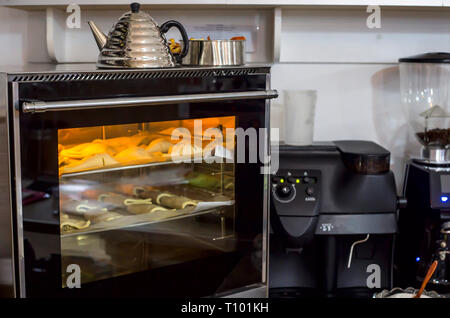 Materie soffi su un vassoio da forno sono cotti in forno. Pasticceria fresca nel bar Foto Stock