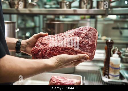 Come scegliere una carne man mano che mostra un grande pezzo di carne fresca pronto per preparare gustose. Ristorante Cucina. Concetto culinario Foto Stock