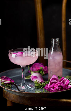 Estate bevande ristoro. Luce rosa rosa cocktail con vino rosato su sfondo scuro. Con rose fiori. Spazio di copia Foto Stock