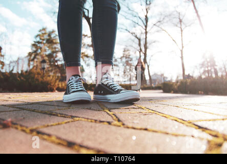 Sneakers nero sulle gambe di una donna che cammina nel parco Foto Stock
