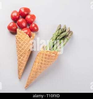 Una sana verdura fresca in coni di cialda su sfondo grigio. Vegane e dieta vegetariana concetto. Vista superiore Foto Stock