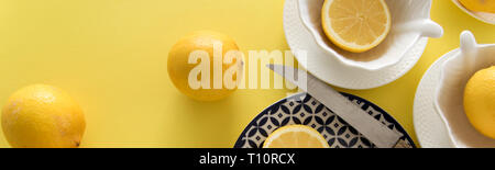 Crudo fresco di limoni e porcellane tablewares fresco su sfondo giallo. Still Life, sfondo, fresh food design Foto Stock