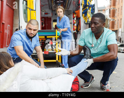 Team paramedico la fornitura del primo aiuto alla donna con la gamba ferita Foto Stock