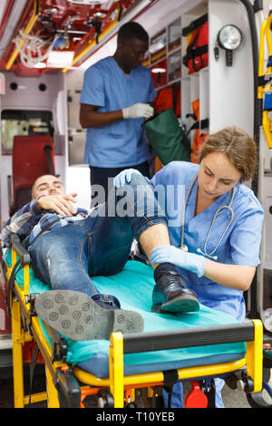 Paramedic team fornire il pronto soccorso per l'uomo in ambulanza auto Foto Stock