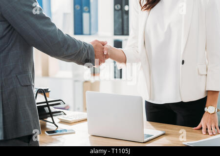 Vista parziale di donna e uomo si stringono la mano in ufficio Foto Stock