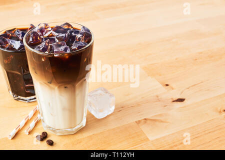 Caffè ghiacciato e il latte macchiato in bicchiere con cannucce su un tavolo di legno. Vari tipi di caffè. Copia spazio per il testo. Foto Stock