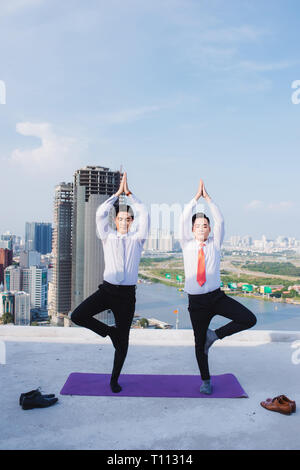 Un giovane imprenditore asiatici facendo sport a tetto Foto Stock