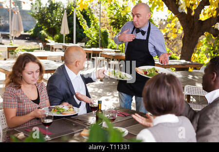Conflitto tra il cameriere e client nel ristorante all'aria aperta Foto Stock