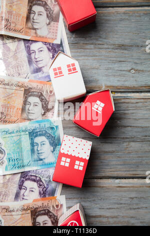 Costo di alloggiamento. Paper Toy house con British moneta note Foto Stock