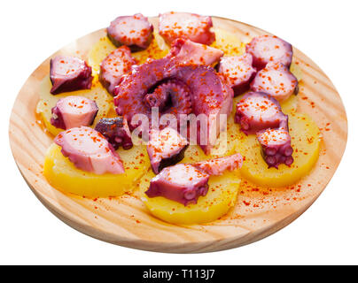 Stile galiziano polpo con patate servita sulla tradizionale piatto di legno. Isolato su sfondo bianco Foto Stock