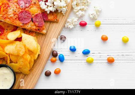 Fast food e malsano concetto di mangiare. Close up di un fast food snack: pizza, popcorn, patatine e caramelle. Assortimento di carboidrati prodotti ba Foto Stock