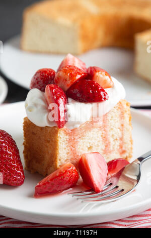 Porzione di angel food cake servito con panna montata e fragole Foto Stock