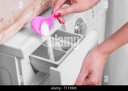 Le mani delle donne sbiancante mettendo in alla macchina di lavaggio. Foto Stock