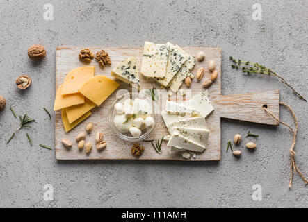 Assortimento di formaggi con i dadi sul pannello di legno Foto Stock