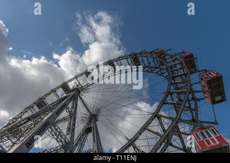 Un enorme metallo vittoriano ruota panoramica Ferris in un grande parco pubblico di Vienna in Austria con un cielo blu e bianchi e soffici nuvole sopra. Foto Stock