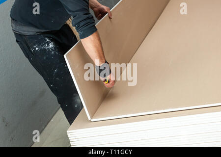 Lavoratore a lavorare per la costruzione di una parete di cartongesso. Foto Stock