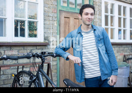 Un giovane uomo si erge tra un carico di biciclette in un deposito bici posizione in un College di Cambridge. Foto Stock