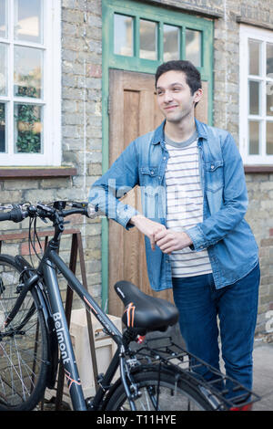 Un giovane uomo si erge tra un carico di biciclette in un deposito bici posizione in un College di Cambridge. Foto Stock