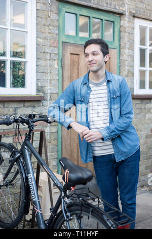 Un giovane uomo si erge tra un carico di biciclette in un deposito bici posizione in un College di Cambridge. Foto Stock