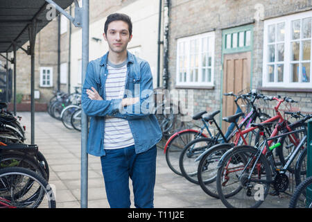 Un giovane uomo si erge tra un carico di biciclette in un deposito bici posizione in un College di Cambridge. Foto Stock