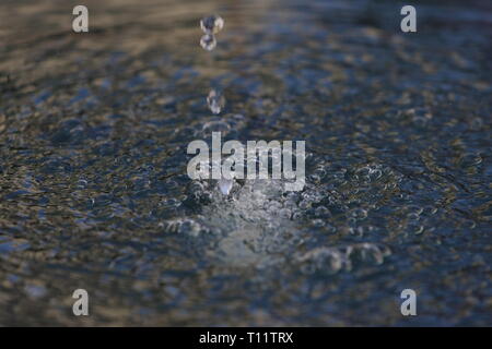 Primo piano di gocce d'acqua che cadono in acqua frizzante Foto Stock