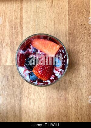 Primo piano di una deliziosa panna cotta dessert con Fragole Lamponi, more di rovo e vaniglia su un faggio elegante tavolo da pranzo Foto Stock