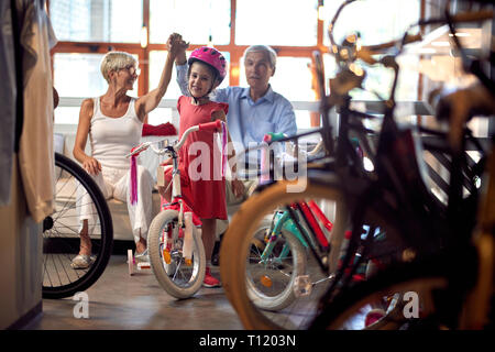 Felice nonni acquisto nuova bicicletta per bambina Foto Stock