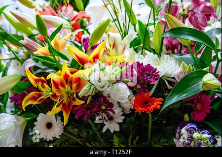 Grande e bel bouquet di crisantemi, orchidee e gerbere con un grande giglio giallo in un negozio di fiori. Foto Stock