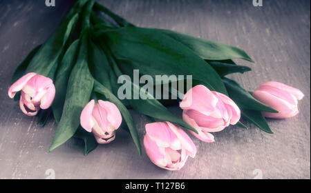 Bella tulipani rosa con foglie verdi sulla superficie del tavolo Foto Stock
