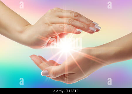 Mani curative con luminosi sunburst su sfondo arcobaleno Foto Stock