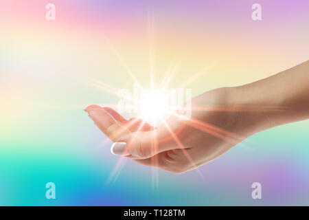 Mani curative con luminosi sunburst su sfondo arcobaleno Foto Stock