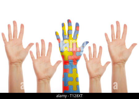 Le mani umane, uno modellato con molti pezzi di un puzzle di diversi colori. Di sensibilizzazione sull'autismo cocept Foto Stock