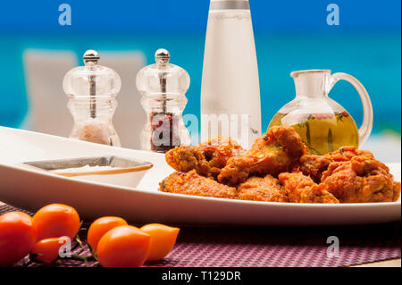 Frittelle di pollo preparato con farina di mais, fritti in olio, servito con patate e salse. Foto Stock