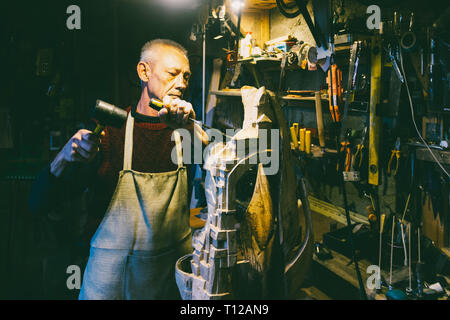 Maestro di legname 50 - 55 anni crea la scultura in legno in officina Foto Stock