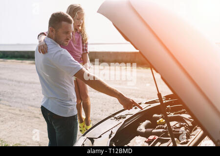 Bello il padre ad insegnare la sua età scolare la figlia di cambio olio motore o riparazione Carrozza famiglia Foto Stock