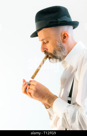 Uomo caucasico con hat fuma un sigaro. Vista laterale. faccia con la barba. Foto Stock