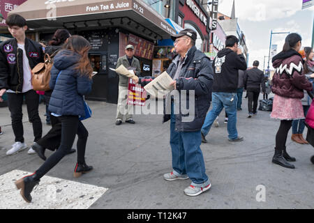 Un uomo sulla Main st. & Roosevelt Ave. in Chinatown mani fuori la lingua cinese volantini. In lavaggio, Queens, a New York. Foto Stock