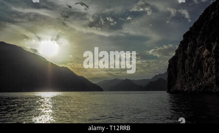 Sun sullo sfondo di montagne e il mare. I Fiordi della penisola di Musandam. Khasab bay. Oman Foto Stock