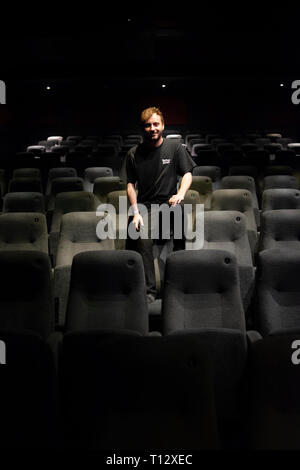 Un elemento maschio di personale si siede in un auditorium vuoto del Duca di Yorks movie theater in Brighton Foto Stock