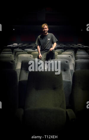 Un elemento maschio di personale si siede in un auditorium vuoto del Duca di Yorks movie theater in Brighton Foto Stock