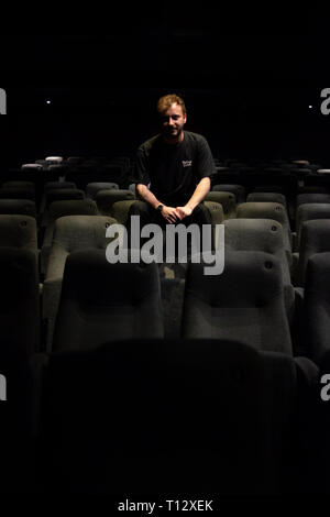 Un elemento maschio di personale si siede in un auditorium vuoto del Duca di Yorks movie theater in Brighton Foto Stock