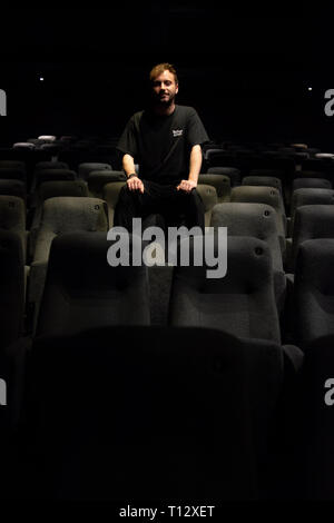 Un elemento maschio di personale si siede in un auditorium vuoto del Duca di Yorks movie theater in Brighton Foto Stock