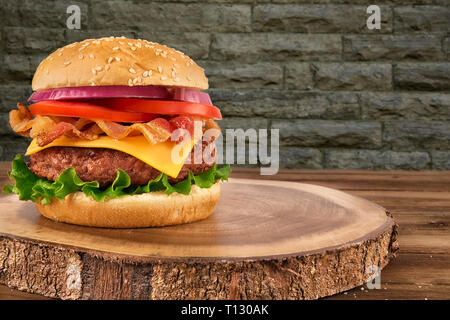 Cheeseburger con polpetta di carne di manzo e pancetta, muro di mattoni in background. Spazio copia il tuo testo. Foto Stock