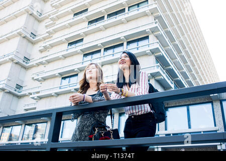 Due giovani studentesse stand al di fuori del loro collegio di moderni edifici su un campus urbano Foto Stock