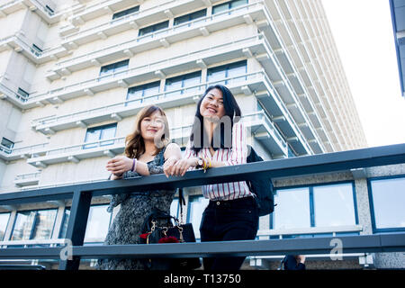 Due giovani studentesse stand al di fuori del loro collegio di moderni edifici su un campus urbano Foto Stock