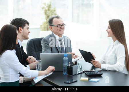 Manager per discutere questioni di lavoro con i suoi assistenti dietro una scrivania Foto Stock