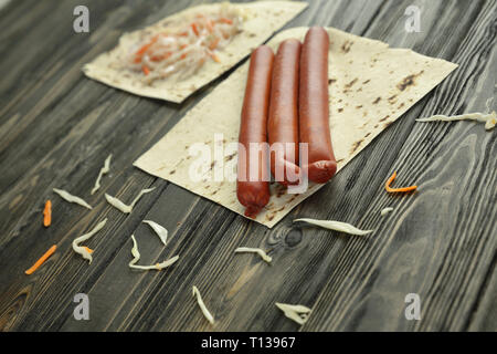 Salsicce affumicate, cavolo e pane pita isolato su sfondo di legno Foto Stock