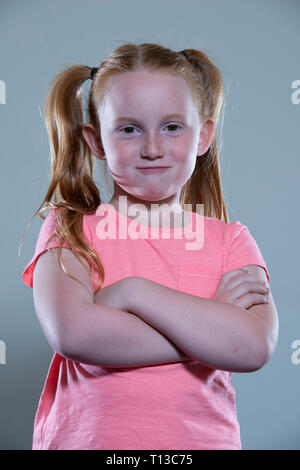 Un dai capelli rossi ragazza con le braccia piegate. Foto Stock