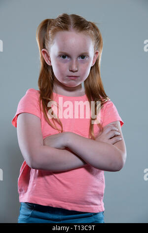 Un dai capelli rossi ragazza con le braccia piegate. Foto Stock